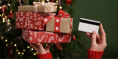 Žena drží v rukou vánoční dárky a kreditní kartu