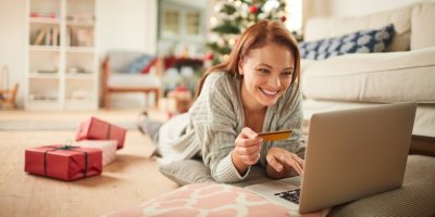 Žena v obývacím pokoji u vánočního stromu provádí nákup online