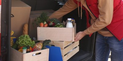 Kurýr rozváží bedny s potravinami dodávkou