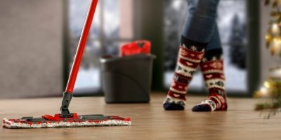 Záběr na ženské nohy ve vánočních ponožkách a mop vytírající podlahu