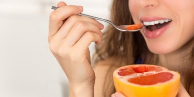 Žena jí grapefruit lžičkou