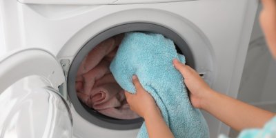 Žena dává ručník do pračky