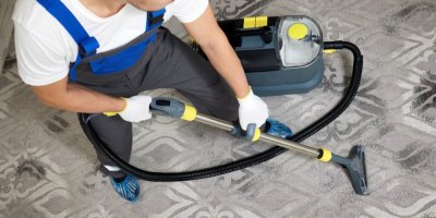 Muž čistí koberec tepovačem