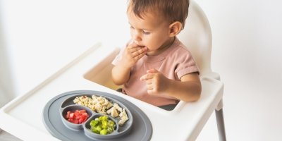 Dítě v židličce u talíře s jídlem