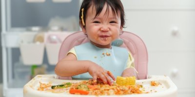 Dítě v židličce a velký nepořádek z jídla