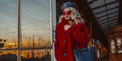 Mladá žena v červeném kabátu a černém koženkovém baretu