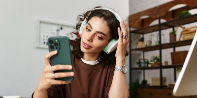 Žena se sluchátky a mobilem v rukou