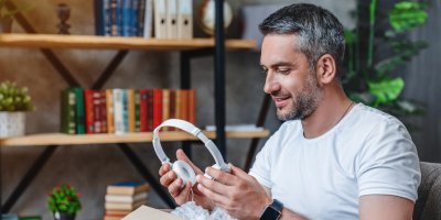 Muž si rozbaluje sluchátka bílá