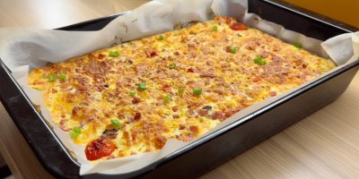 Pečený pokrm z vajec, sýra, zeleniny a uzeniny na plechu vyloženém pečicím papírem