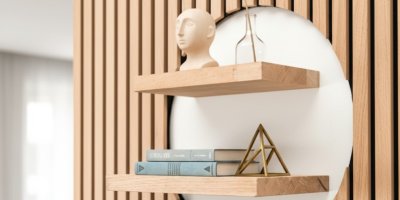 Stěna s akustickým panelem s kruhovým výřezem, dvě poličky s knihami a dekoracemi