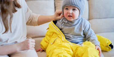 Matka obléká batole do zimního oblečení