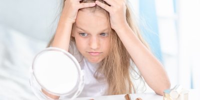 Mladá frustrovaná dívka se dívá do zrcátka