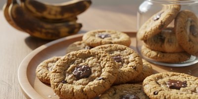 Sušenky s kousky čokolády, v pozadí přezrálé banány