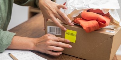 Žena lepí na balíček lístek s nápisem vrácení