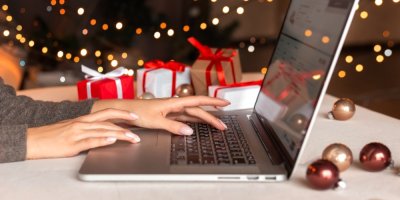 Žena s otevřeným notebookem, v pozadí vánoční dárky