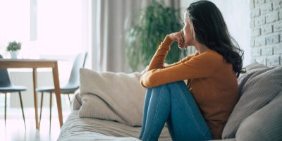 Mladá žena sedí smutně na gauči