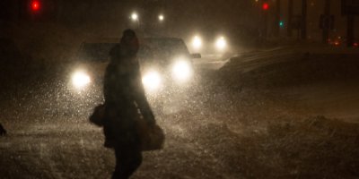 Člověk kráčí večer po zasněžené vozovce 