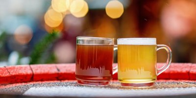 Dva horké nápoje ve skleněných hrnečcích na vánočním trhu