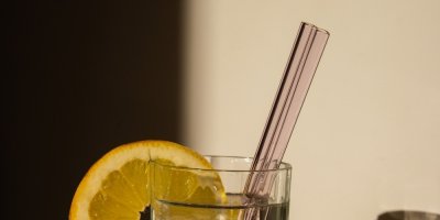 Dvě skleněná brčka ve sklenici vody s plátkem citronu