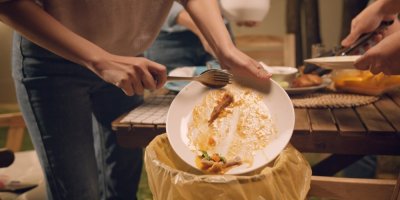 Žena vyhazuje zbytky jídla z talíře do koše