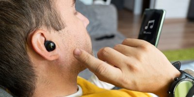 Muž s bezdrátovými sluchátky v uších si pouší hudbu