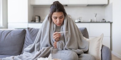 Nemocná mladá žena si měří teplotu