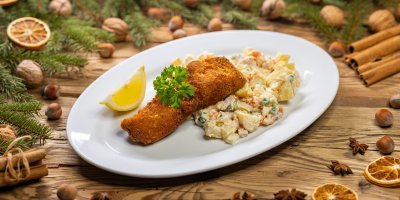 Smažený kapr a bramborový salát na bílém talíři