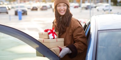 Žena vystupuje z auta a drží v rukou dárky