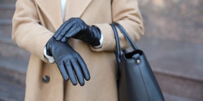 Žena v béžovém zimním kabátu a černých kožených rukavicích