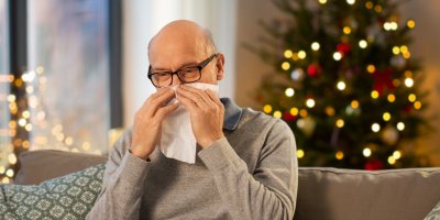 Starší muž smrká před vánočním stromečkem