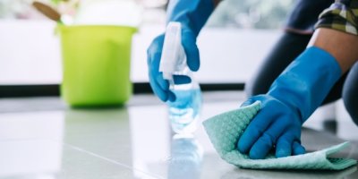 Muž čistí podlahu utěrkou a čisticím prostředkem