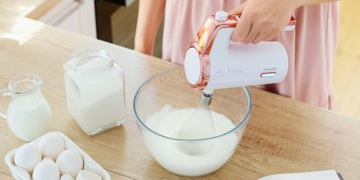 Osoba šlehá krém v míse bezdrátovým šlehačem