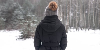 Žena zezadu s čepicí s bambulí v zimě