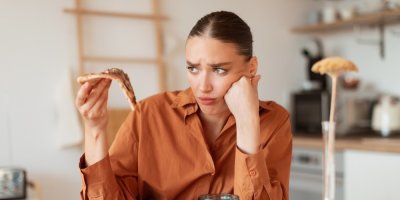 Žena drží v ruce kousek pizzy