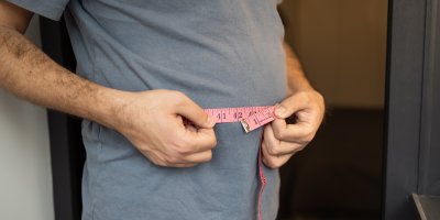 Muž se měří metrem v pase