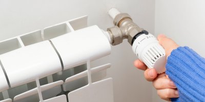 Ruka upravuje teplotu na radiátoru