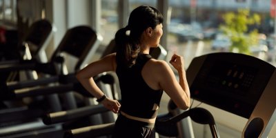 Žena běží na pásu v posilovně 