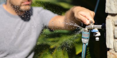 Muž pouští venkovní kohoutek