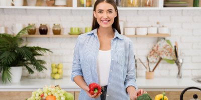 Žena v kuchyni drží v ruce papriku