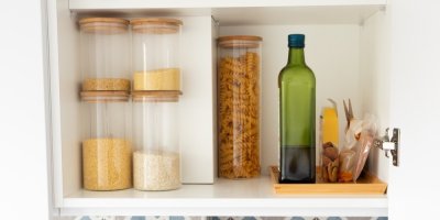 Potraviny ve skleněných nádobách v kuchyňské skříňce