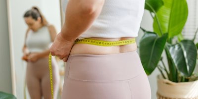 Žena v legínách si měří obvod pasu