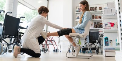 Ortopedka nasazuje kolenní ortézu mladé klientce