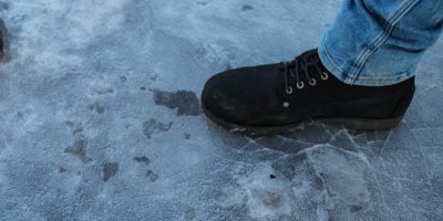 Noha v zimní obuvi na zledovatělém povrchu