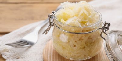 Sklenice s kysaným zelím, položená na dřevěném prkénku