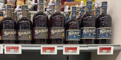 Lahve rumu Republica v regálu supermarketu