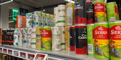 Plechovky míchaných nápojů v regálu supermarketu