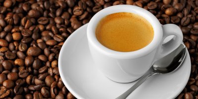 Espresso v hrníčku leží na kávových zrnech