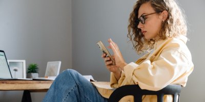 Mladá žena scrolluje na mobilním telefonu