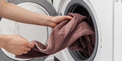 Člověk vkládá ručník do pračky