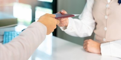 Žena podává cestovní pas zaměstnankyni letecké společnosti